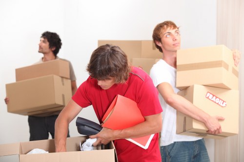 Removal team carrying boxes down a London townhouse staircase